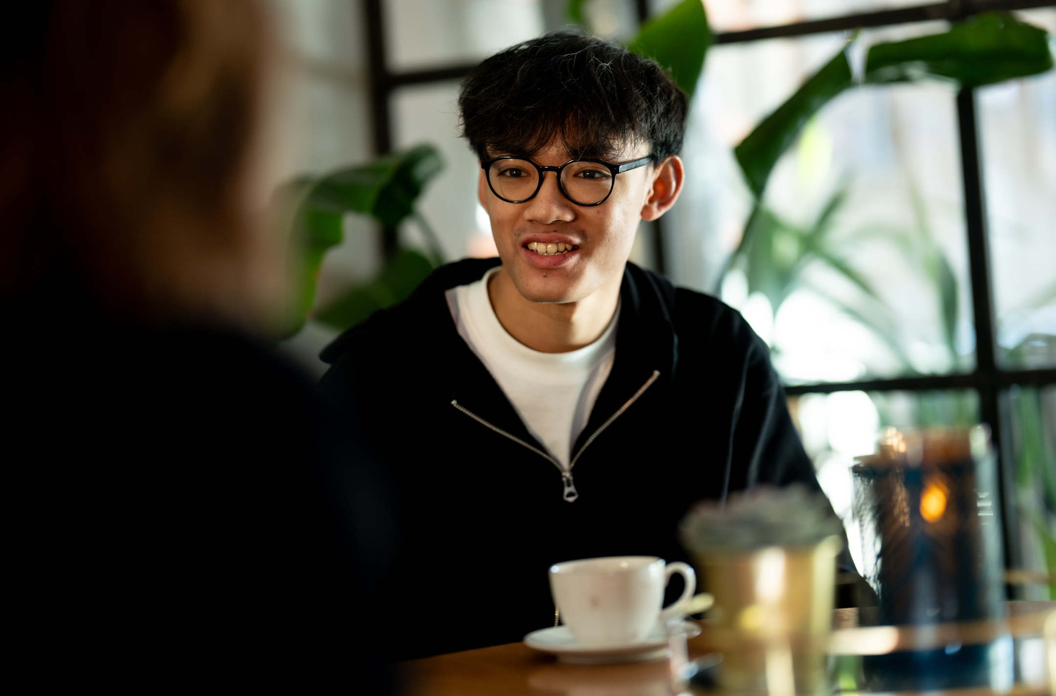 Tayza Naing, ung kompositör, sitter koncentrerat vid ett cafébord under repetitionerna av föreställningen