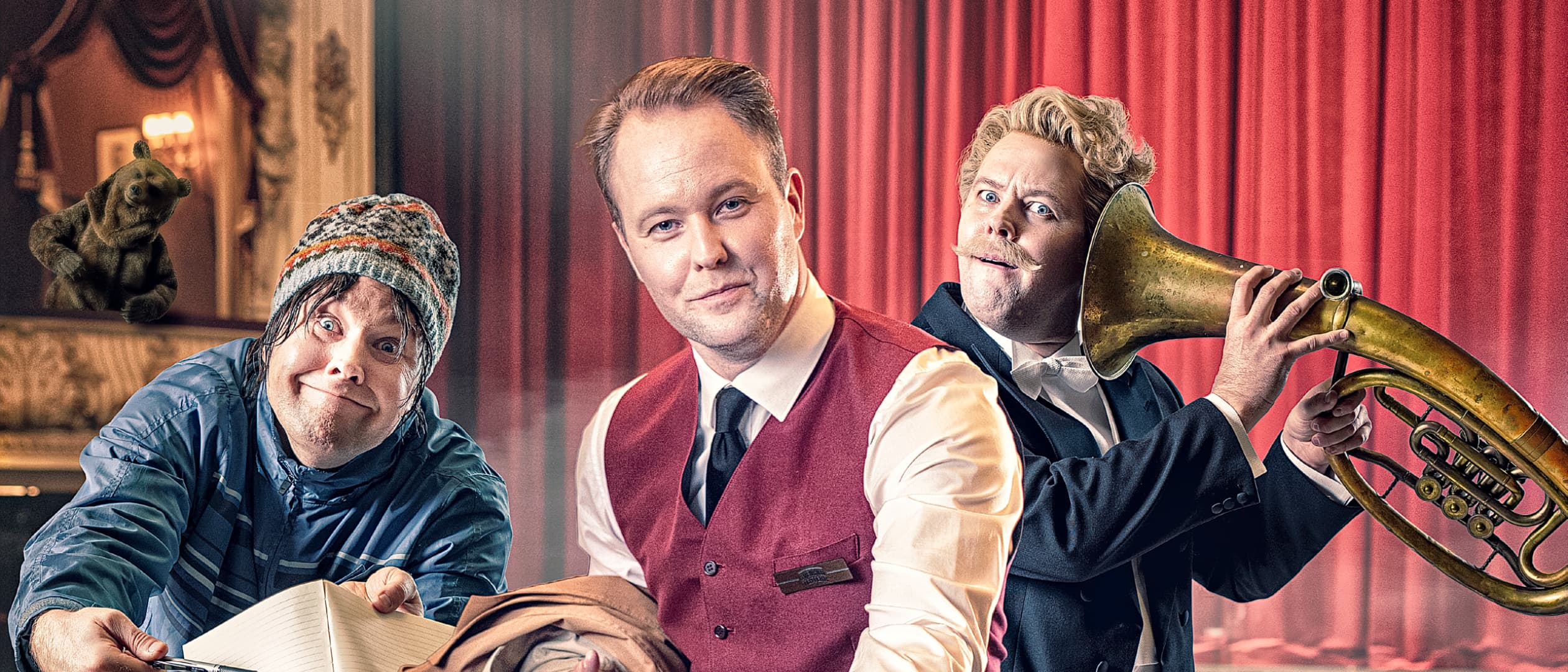 Näyttelijä Dennis Nylund kolmena eri henkilönä teatterisalissa, jossa on punainen esirippu: nimikirjoitusmetsästäjä muistilehtiön kanssa, saliemäntä punaisessa liivissä ojentamassa kättään ja muusikko, jolla on suuri messinkisoitin korvaa vasten. Taustalla näkyy karhu.