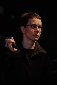 Henkilö pitelee mikrofonia kädessään hämärässä ympäristössä.