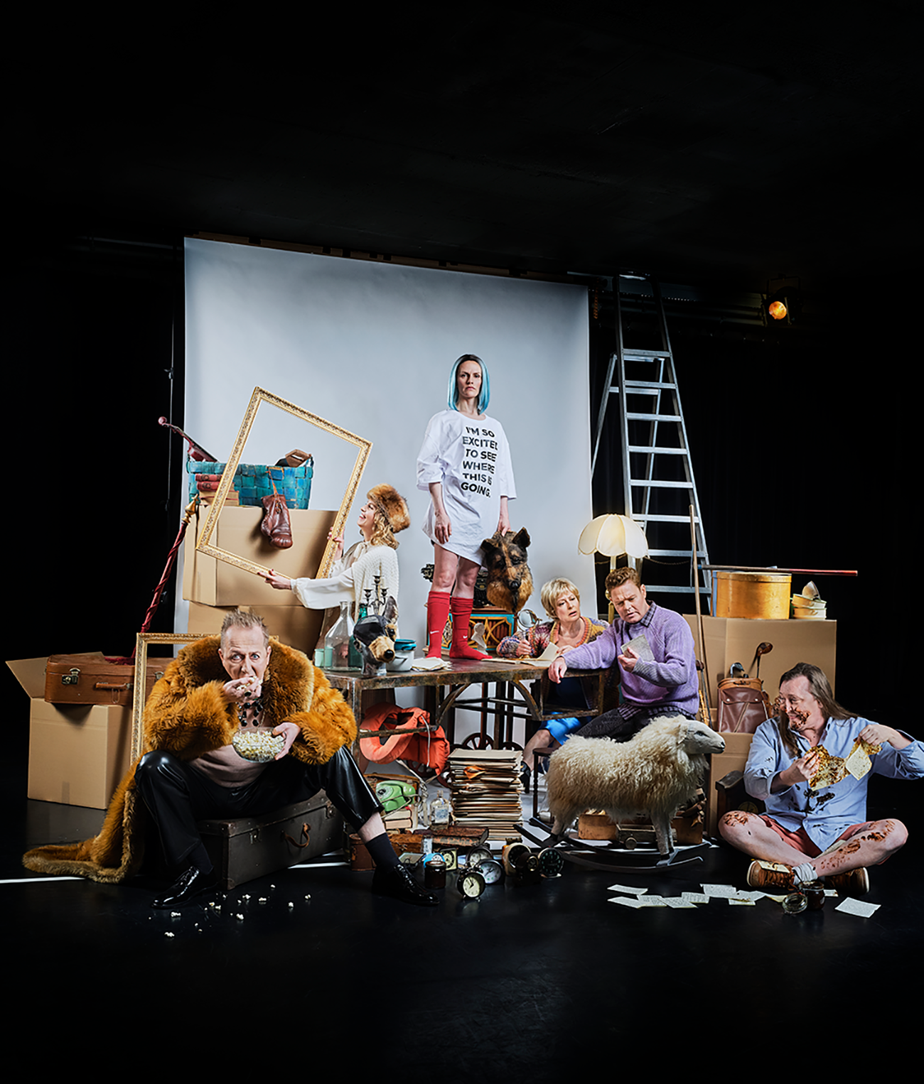 Ensemblen i Nattland presenteras i en scenbild fylld av symboliska objekt, där vardagliga ting blandas med visuella överraskningar och skapar en rik, lekfull och kaotisk värld som speglar föreställningens tematik.